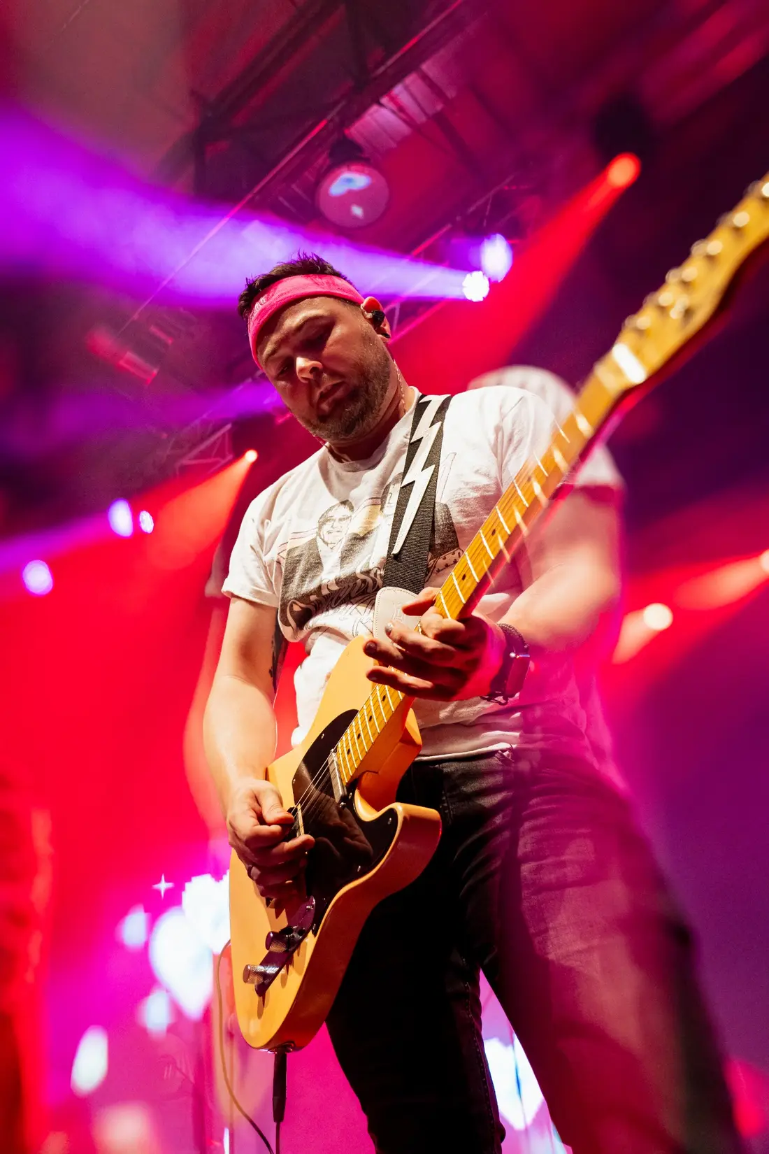 Sven spielt Gitarre im roten Bühnenlicht